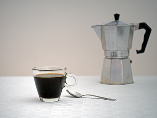 Black coffee, blurry coffee espresso coffee maker behind.