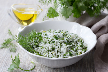 Rice with greens in a white bowl on a wooden table