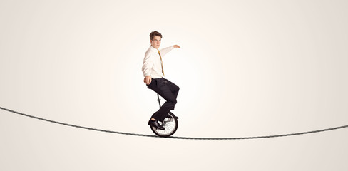 Extreme business man riding unicycle on a rope - Powered by Adobe