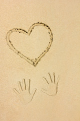 Herz und Handabdrücke im Sand 