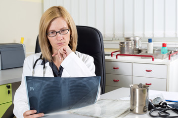 Pensive Doctor With Hand on Chin Looking at Patient's Lung X-ray