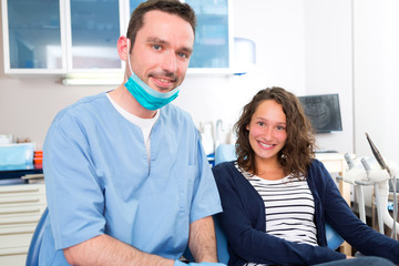 Portrait of a young attractive dentist in his office with patien