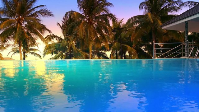 Luxury hotel pool with blue water and palm trees around. Tropical island