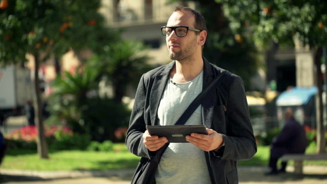 Young male tourist checking map on tablet computer in city
