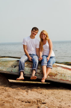couple on a beach sitting on old boat