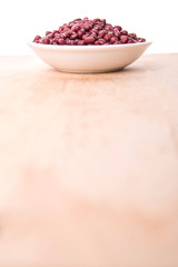 Red adzuki beans in white bowl over wooden background