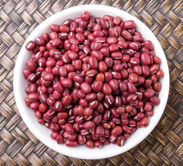 Red adzuki beans in white bowl over wicker background