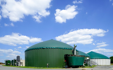 Biogasanlage mit Gärstoffzufuhr-Behälter vor blauem Himmel