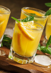 Orange drink with soda, mint and fruit, selective focus