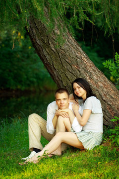 young couple sitting under tree