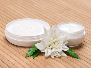 Obraz na płótnie Canvas Open jars of cream with white flower and fern leaves