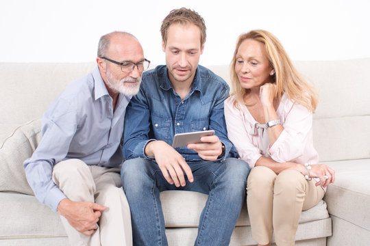 Älterer Sohn zeigt etwas auf dem Tablet seiner Eltern