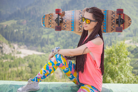 Hippie young and beautiful girl with longboard skateboard at mountain