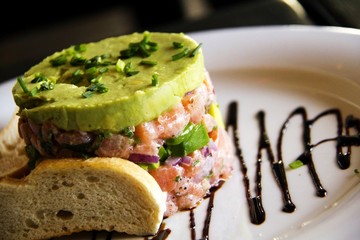 Appetizer from raw salomon with avocado cream and toast on the white plate