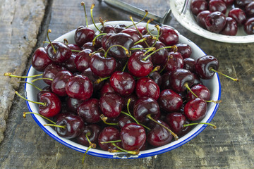 Fresh cherries in a bowl on wooden table - closeup