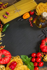 Raw pasta with ingridients on black board