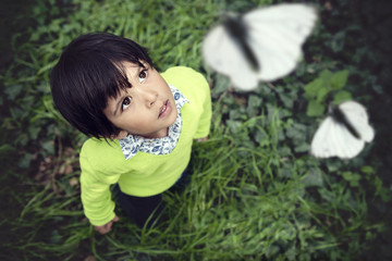 3 year old toddler looking up at white butterflies flying