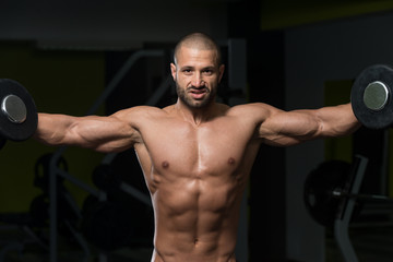 Fototapeta na wymiar Male Bodybuilder Doing Heavy Weight Exercise For Shoulders