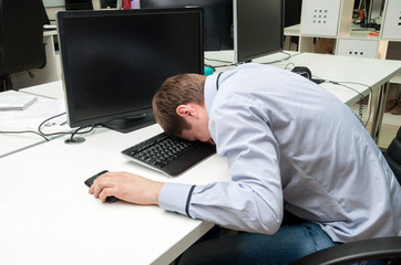 Young handsome man speeping upon a keyboard
