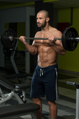 Fototapeta na wymiar Male Bodybuilder Doing Heavy Weight Exercise For Biceps