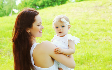 Happy loving mother and baby together outdoors in sunny summer d
