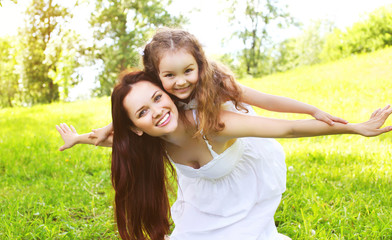 Obraz premium Happy smiling mother and daughter child having fun together outd