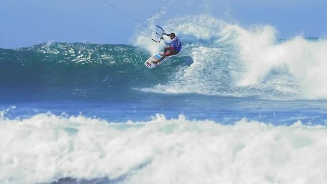 Watersport activity, skillful male kitesurfer freestyle sailing on ocean waves
