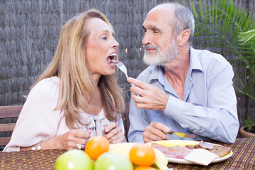 Obraz na płótnie Canvas Elderly couple having food on terrace