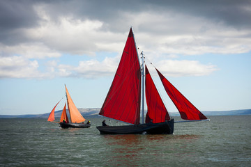Traditional wooden boats with read sail.