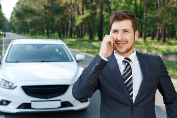 Businessman talking per mobile phone near car