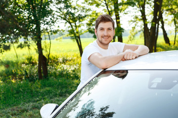 Happy young man near his car