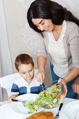 Mother putting salad on plate of her son