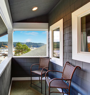 Covered Porch Of The Blue Siding Home With Two Chairs.