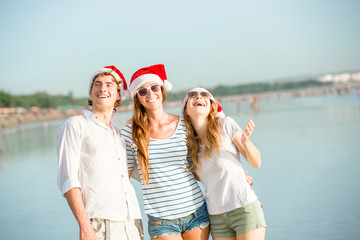 Obraz premium Group of happy young people in christmass hats on the beach