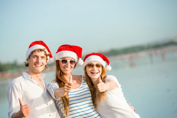 Obraz premium Group of happy young people in christmass hats on the beach