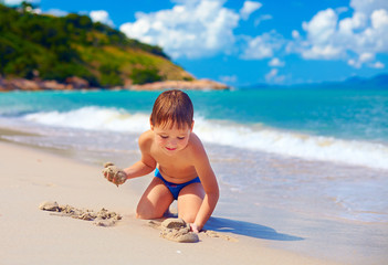 smiling kid playing in sand on tropical island beach