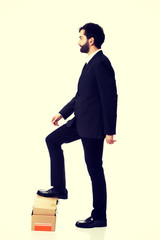 Young businessman standing on stack of books.