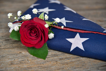 Naklejka premium czerwona róża w składanej amerykańskiej flagi