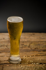 Glass of light beer on black background