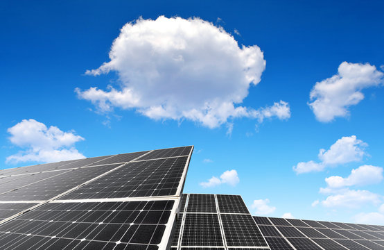 Solar panels against blue sky with clouds