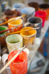 Work table of a pottery decorator of Caltagirone with different color containers and paintbrushes