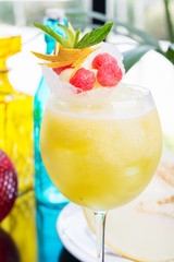refreshing glass of bright juicy melon smoothie or lemonade with ice on a table at a restaurant with the decor of the bright dishes and pieces of melon