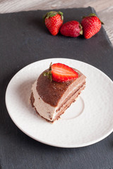 Chocolate cake with strawberry on wooden table, vertical