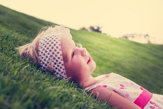 Little beautiful girl lies on the  green grass. The image is tin