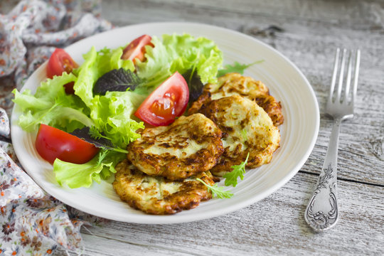 zucchini pancakes and fresh vegetable salad in white plate 