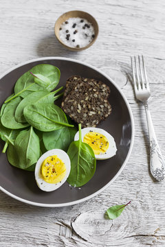 healthy snack - fresh spinach and  egg on a light wooden background