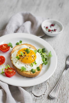 toast with egg and tomatoes on a light wooden surface