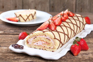 Homemade sponge roll with chocolate patterns, strawberries and cottage cheese cream