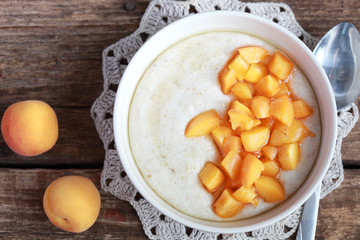 Oatmeal with apricots and honey on a wooden table, breakfast. Ru
