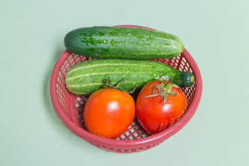 fresh tomato and cucumber on the red basket on the green table